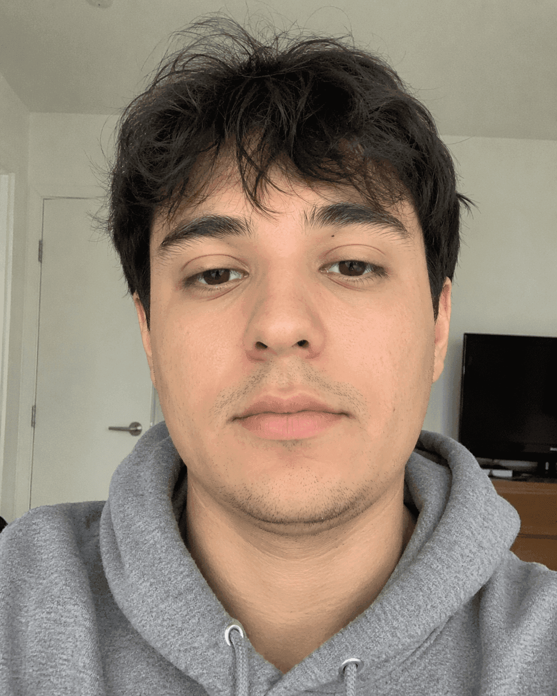 Before photo: casual selfie of a guy with a soft jawline standing in his living room