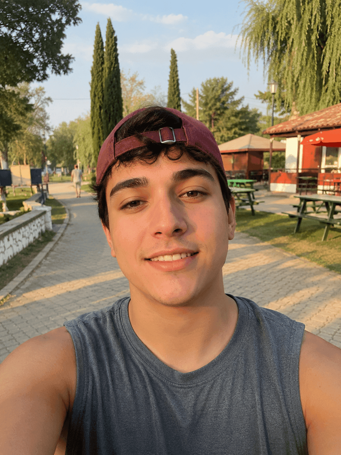 Before jawline filter: man in a cap walking in a park with a reasonably sharp jawline