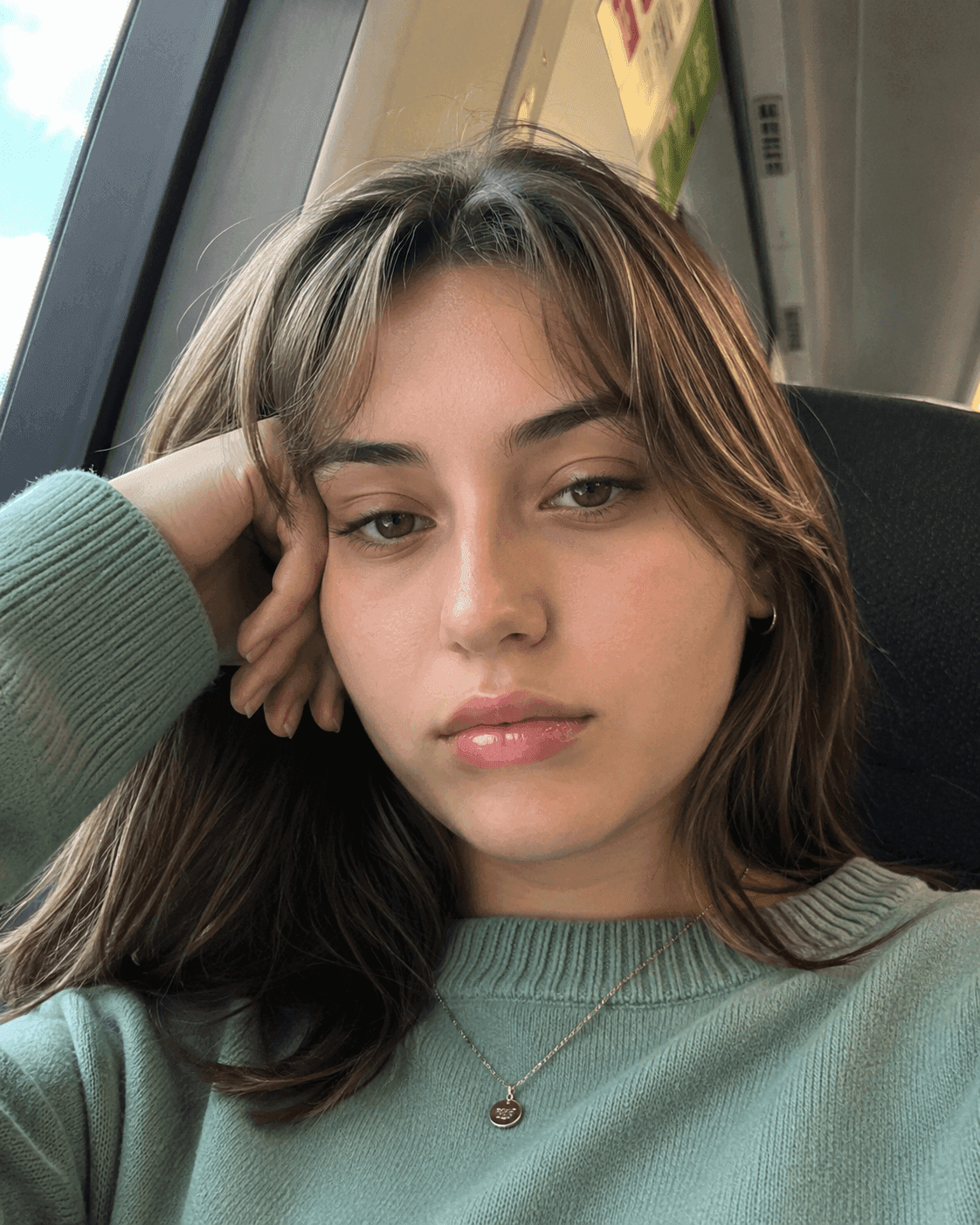 Before jawline filter: woman on a train resting her head on her hand with a round jawline