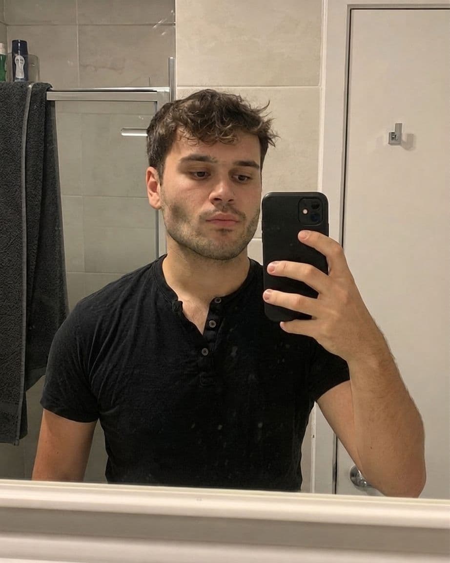 After AI jawline editor: man's bathroom mirror selfie with a strong, defined jawline