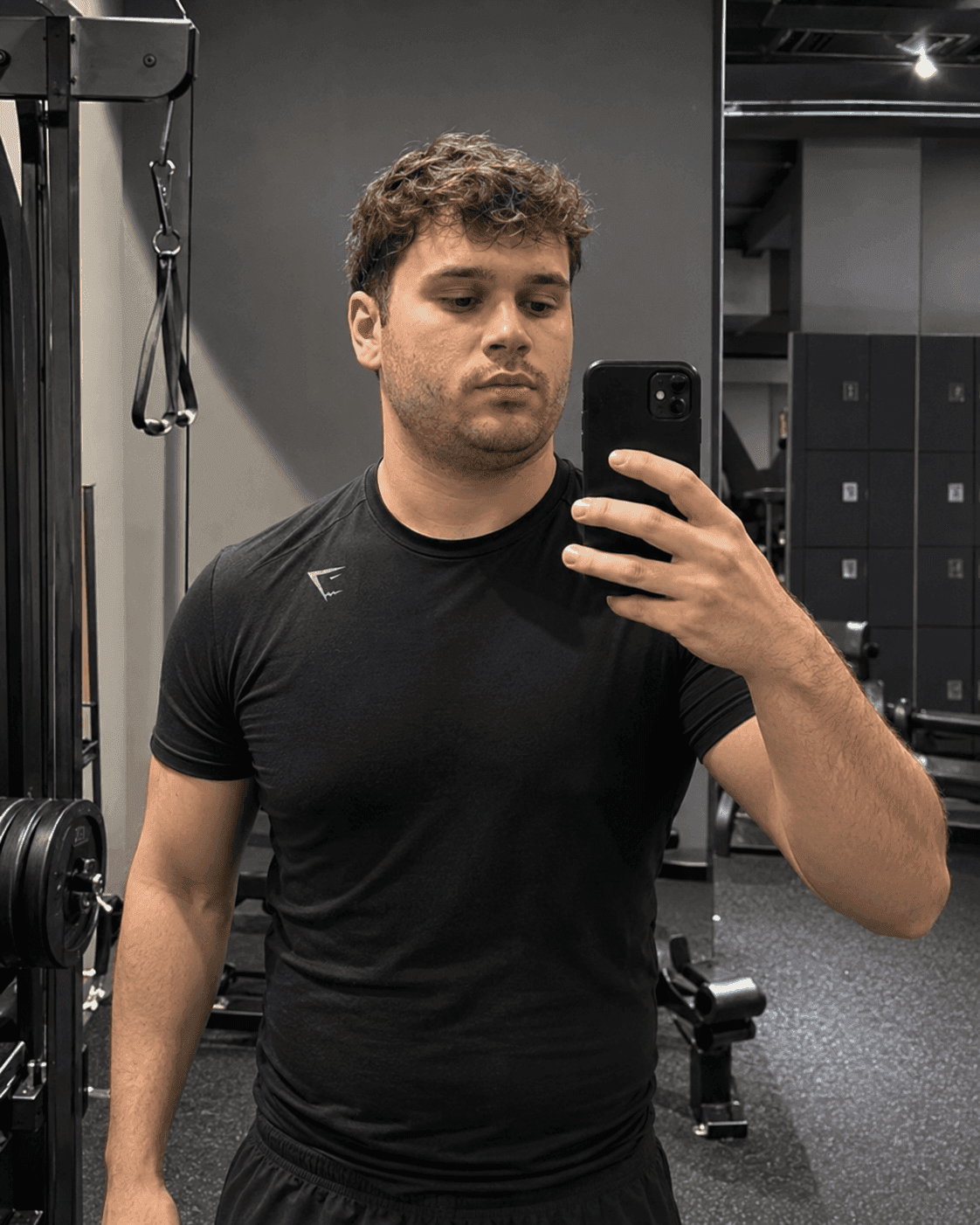 Before jawline enhancer: man's gym mirror selfie with a softer lower face